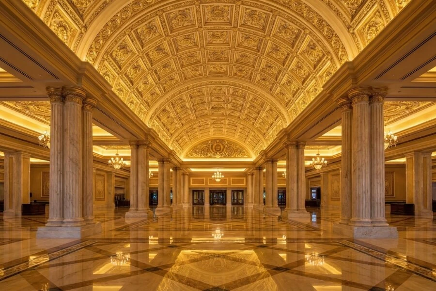 Grand casino entrance lobby with high vaulted ceilings covered in intricate faux gold ceiling tiles to create a sense of luxury and grandeur.