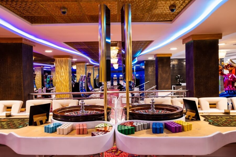 Ornate commercial ceiling tiles above casino roulette tables.