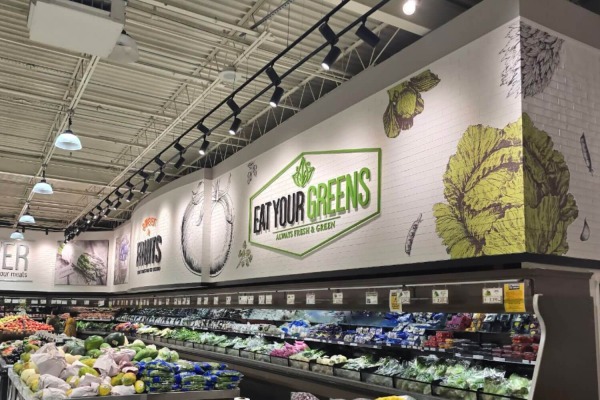 Wide view of a modern supermarket produce aisle featuring durable white faux brick wall panels by Talissadecor.