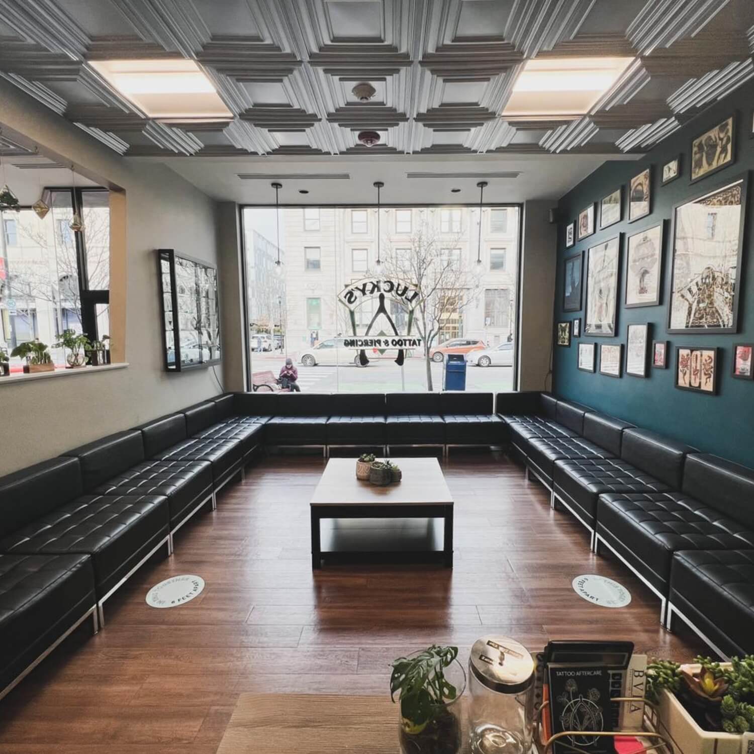 Stylish waiting area of a tattoo salon featuring dark leather couches and beautiful silver tin ceiling tiles.