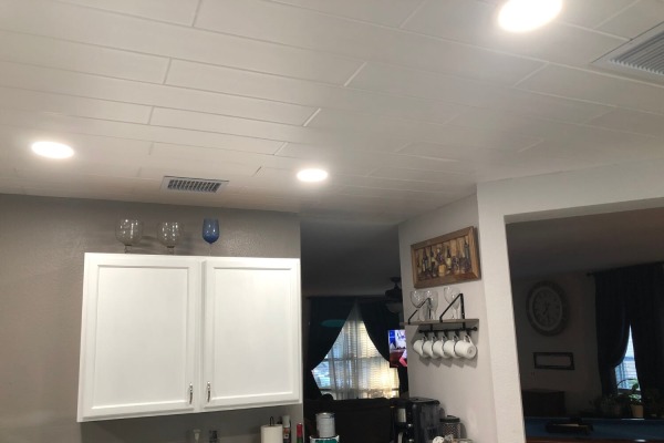 Kitchen remodel featuring plain white styrofoam ceiling planks complementing white cabinetry and grey walls.