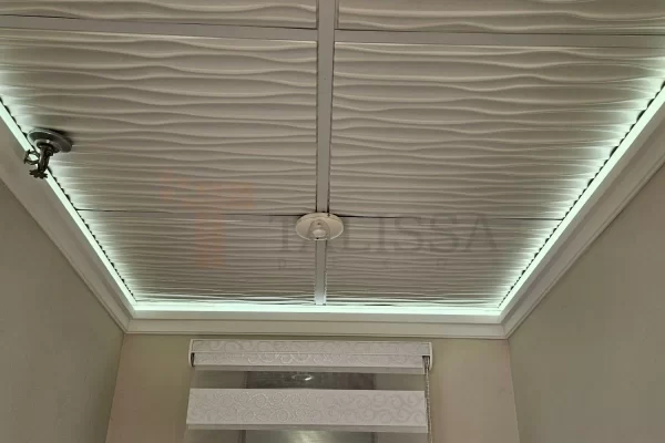 Front view of a 3D wave patterned drop ceiling enhanced by the ambient glow of LED crown molding, utilizing the 04-915 High Density Polymer Crown Molding.