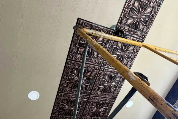 Work in progress showing the installation of traditional copper faux tin ceiling panels on a residential sunroom ceiling.