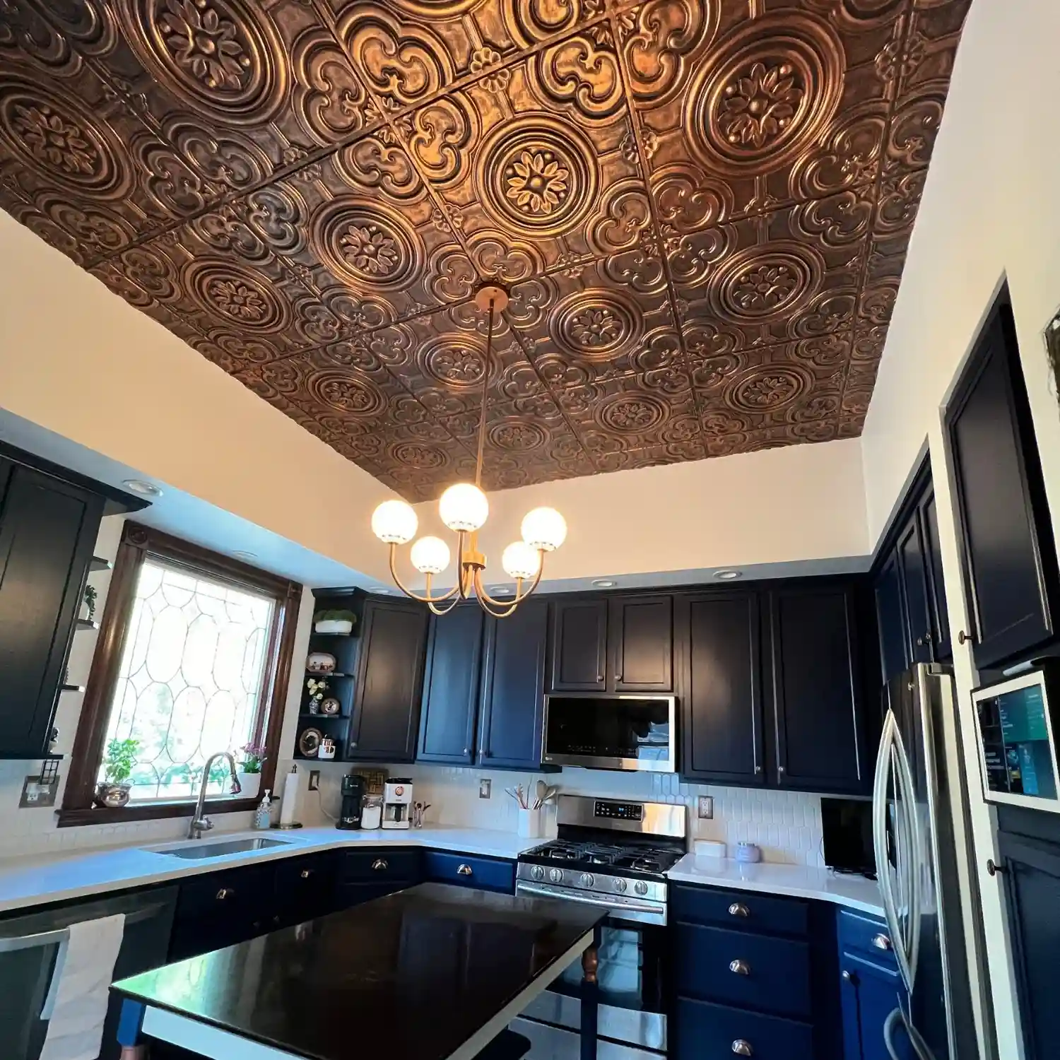 Stunning residential kitchen showcasing an elegant chandelier illuminated against a beautiful rustic copper ceiling cover