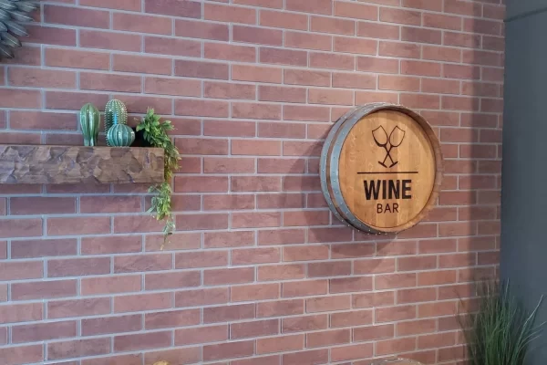 Close-up view of textured brown faux brick wall panels featuring a rustic floating shelf and wine bar wall decor.