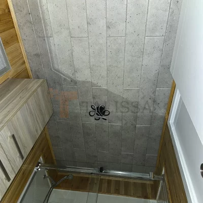 Modern washroom ceiling in Chateau-Richer featuring Concrete Look Foam Ceiling Planks installed above a glass shower with wooden accents.