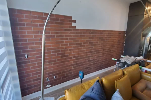 DIY installation in progress showing lightweight brown faux brick wall panels being applied to a 150 sq ft accent wall.