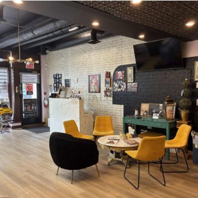 Cozy barbershop salon waiting area with yellow chairs, accented by an elegant, vintage-style antique copper tin ceiling overhead.