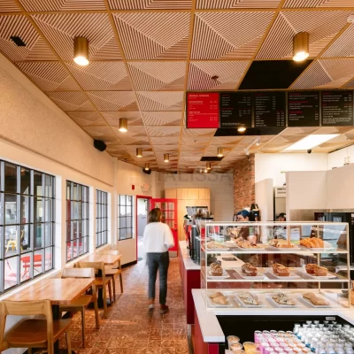 Customers ordering at a stylish coffee shop counter under a stunning geometric faux tin ceiling installation.