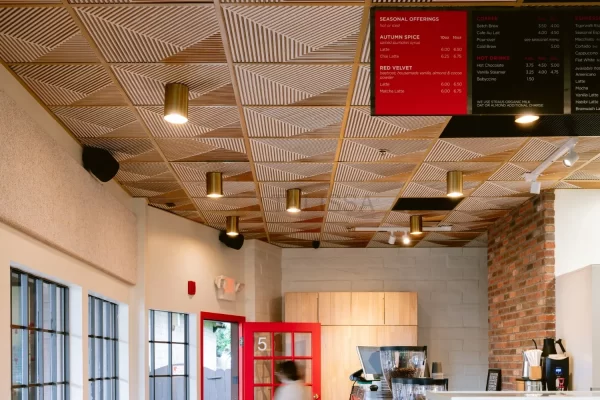 Warm and inviting entrance of a modern cafe showcasing a seamless installation of patterned PVC ceiling tiles overhead.
