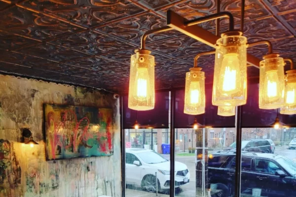 Cozy dining area inside a Downtown Toronto pizzeria illuminated by soft lighting, highlighting the stunning smoked copper tin ceiling above the seating area.