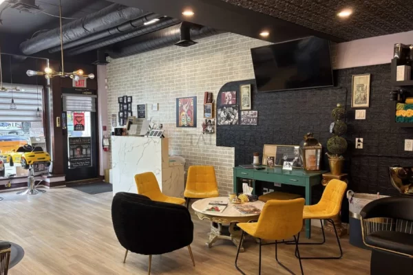 Another view of the stylish salon's waiting room in Toronto, showcasing the dark, detailed ceiling aesthetic that complements the brick-style walls.
