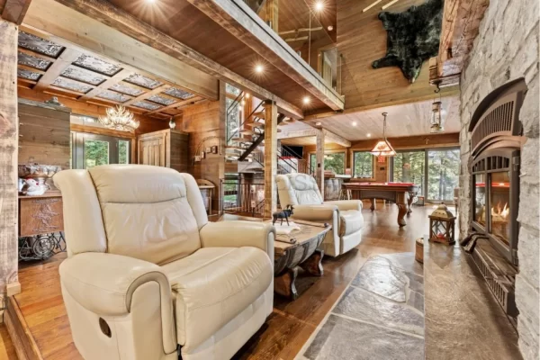 Cozy luxury lodge living area seamlessly connecting to the entrance, highlighted by beautiful TD22 Rustic Tin Ceiling Tiles that complement the natural wood and stone fireplace.