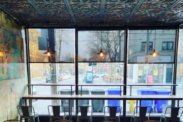 Window seating view inside a Downtown Toronto pizzeria, blending urban street views with a prominent vintage smoked copper tin ceiling.