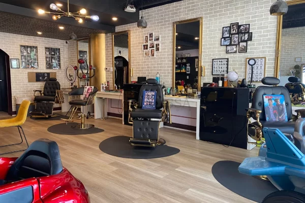 Elegant barbershop salon in Toronto featuring gold-accented styling stations and a stunning antique copper tin ceiling.