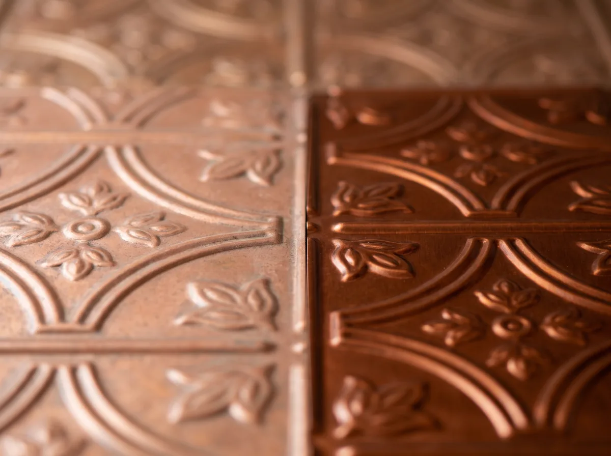 A softened section of faux copper ceiling tile next to an unfaded section