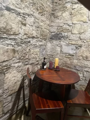 Castle Stones wall mural wrapping the corner behind a round wooden table with candles and a wine bottle